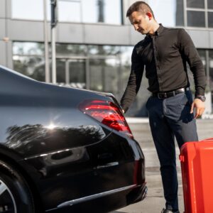 Chauffeur packs a suitcase into luxury car