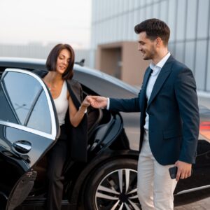 Businessman helps a woman to get out of a car